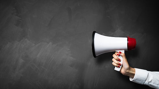 Debattartikel. En hand som håller i en megafon