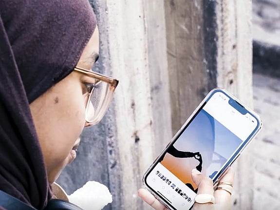 En tjej kollar på bilder i telefon.