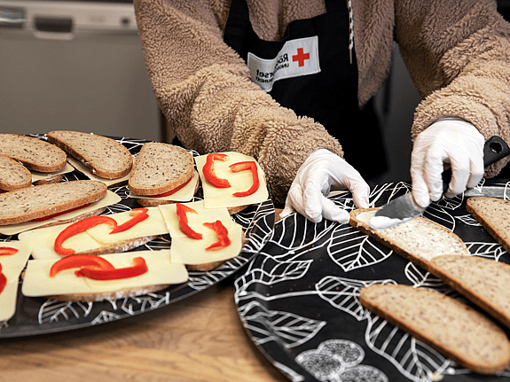 Person gör mackor till Röda Korsets Ungdomsförbunds frukostklubb.