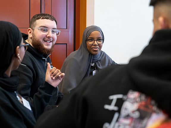 Personer sitter tillsammans och skrattar på Röda Korsets Ungdomsförbunds årliga helgläger för alla engagerade.