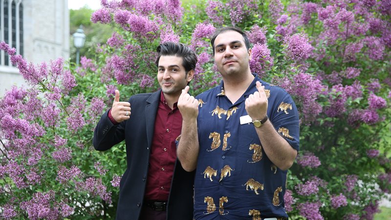 Två glada personer står framför en syrénbuske