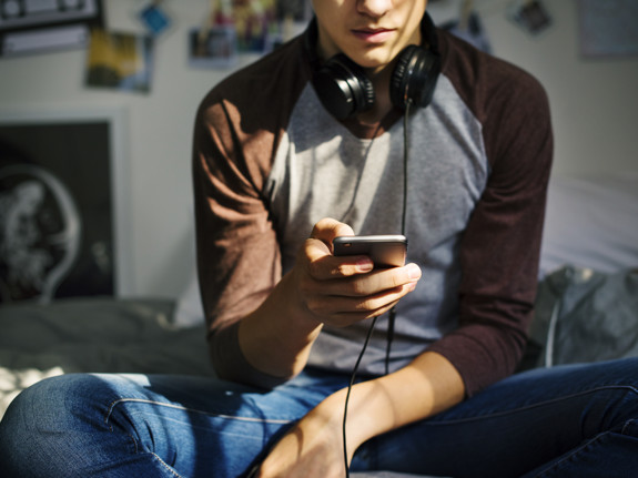 En ung person är inne på sin mobil och söker stöd. Röda Korsets Ungdomsförbund kan stötta unga på olika sätt.