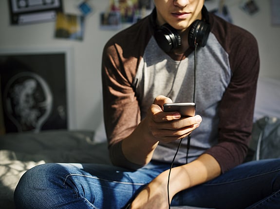 En ung person är inne på sin mobil och söker stöd. Röda Korsets Ungdomsförbund kan stötta unga på olika sätt.